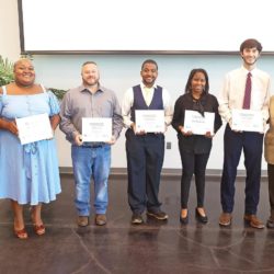 Golden Triangle Coding Academies graduates line up and hold their certificates smiling.