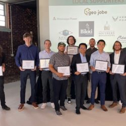 Gulf Coast Coding Academies graduates line up and hold their certificates smiling.