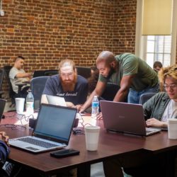 MCA Instructors hovers over students at an open laptop